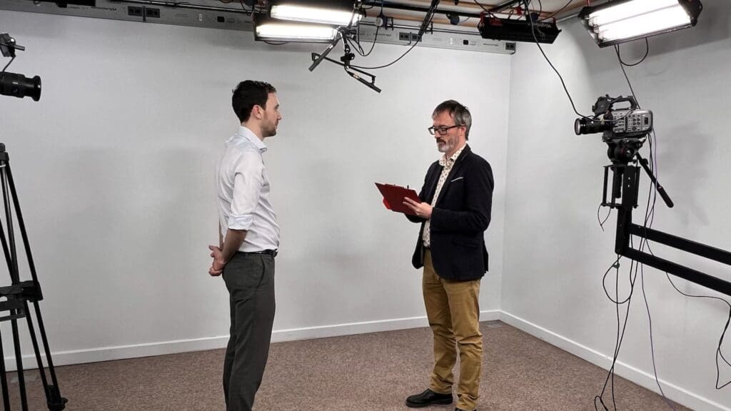 Two men in professional video recording soundproof studio.